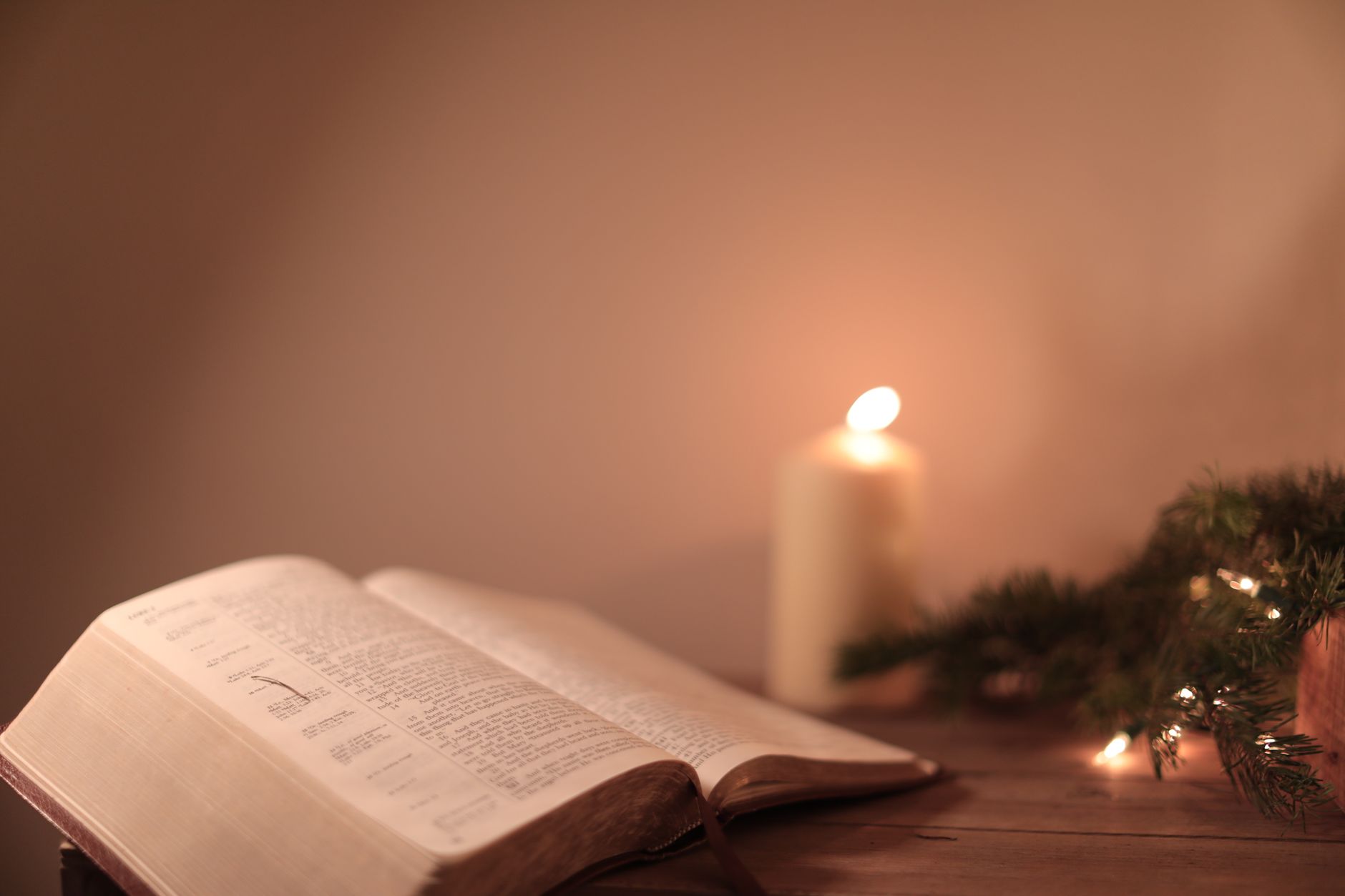 An open Bible lit by warm candlelight at night