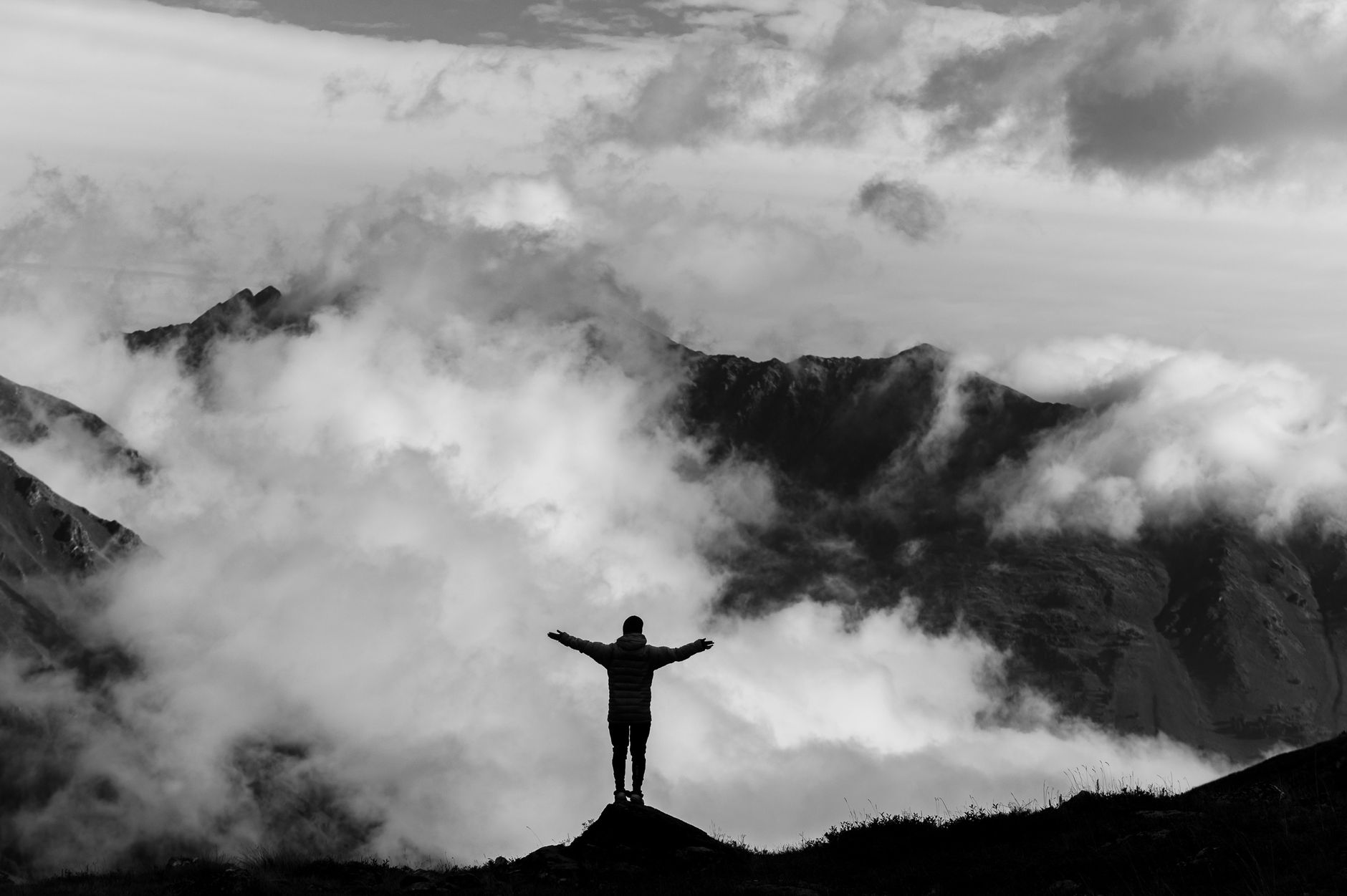 A lone hiker silhouetted against majestic mountains, embracing nature's grandeur
