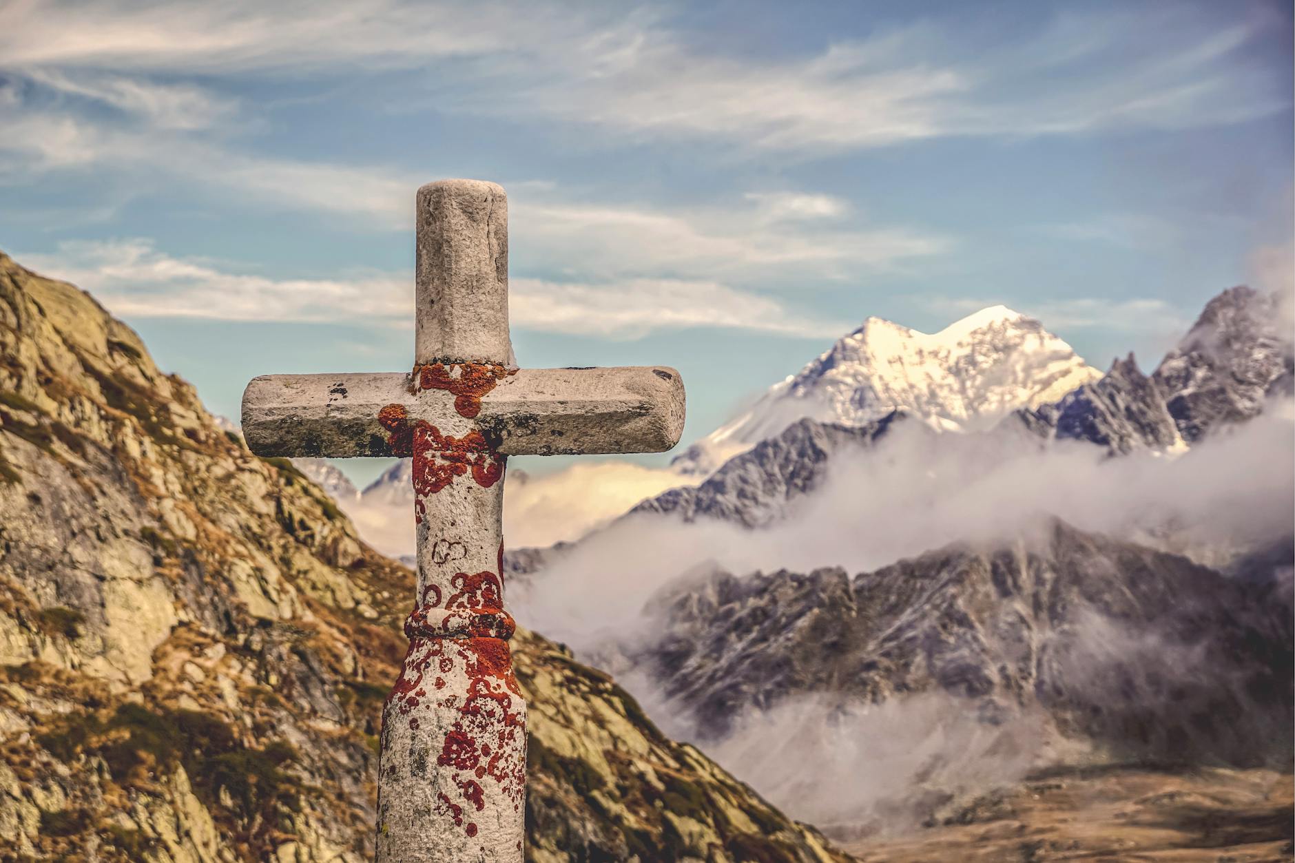 A stone cross standing on a mountain peak surrounded by clouds, trusting God with what you love most