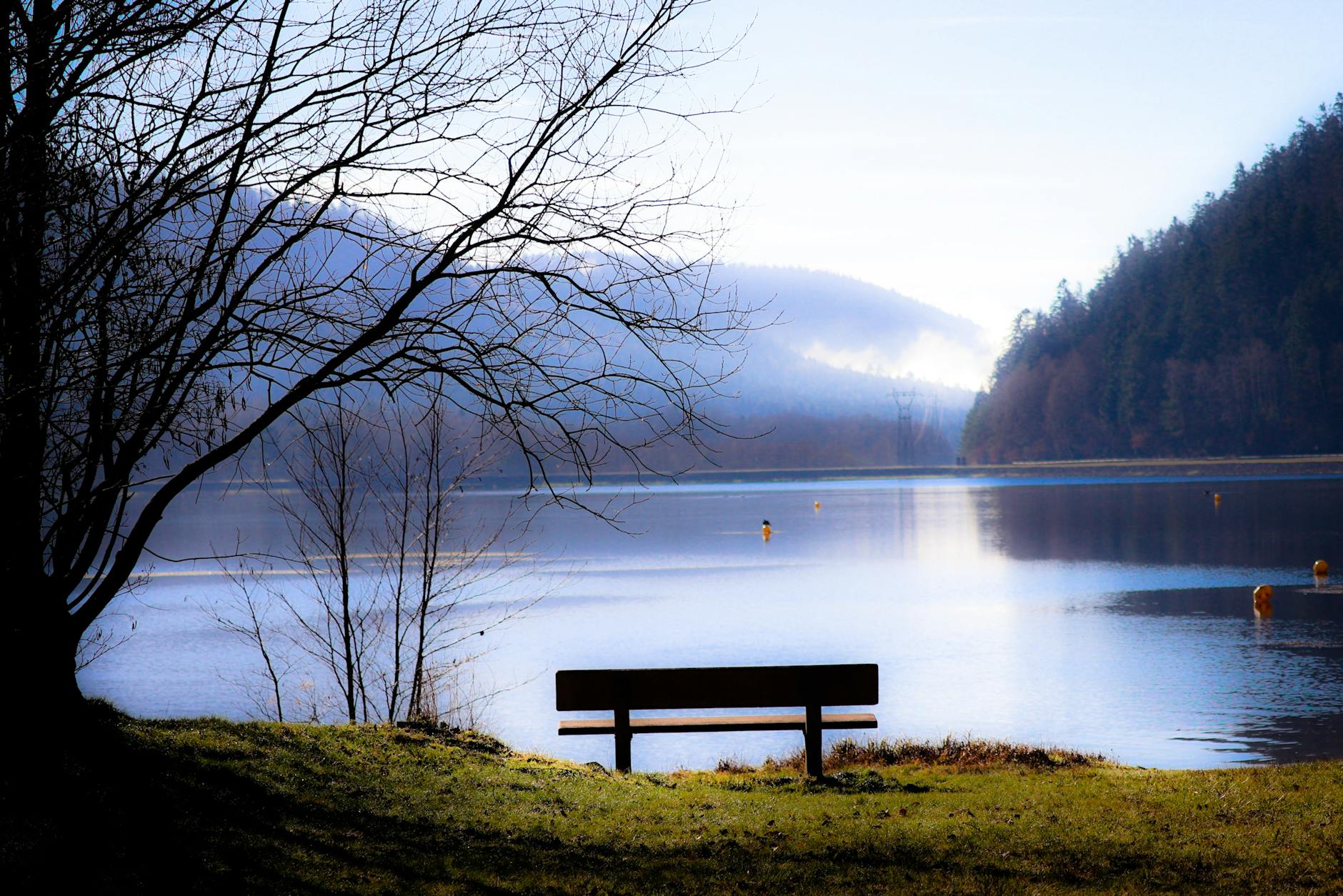 Serene lake at sunrise with an empty bench, finding stillness and peace in God's presence